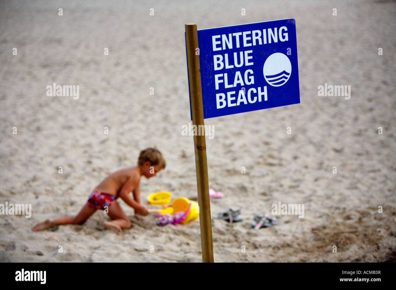 eintretende blaue Flagge Strand anmelden Beitrag am Weststrand Strang Portrush mit kleiner Junge spielt im Hintergrund Stockfoto