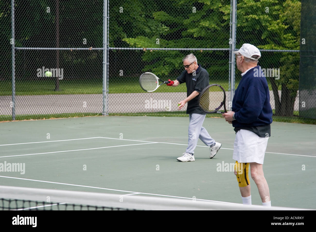 Ältere Menschen im Ruhestand Männer spielen eine Doppel Tennis-Spiel im Rahmen eines senior Olympics Turnier bei einer anhaltenden Pflegeeinrichtung Stockfoto