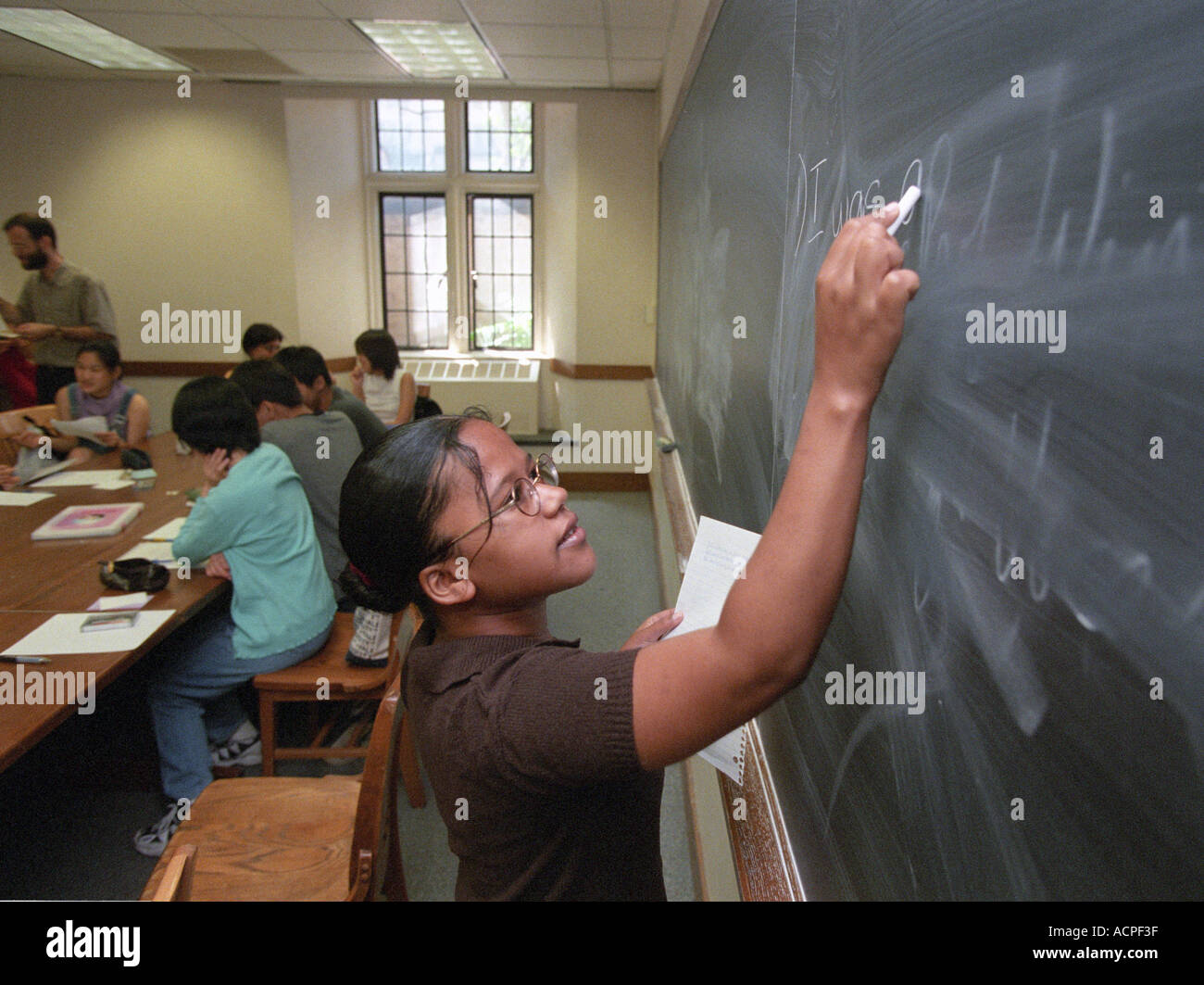 Junge Lehrer schreibt an die Tafel im Klassenzimmer Stockfoto