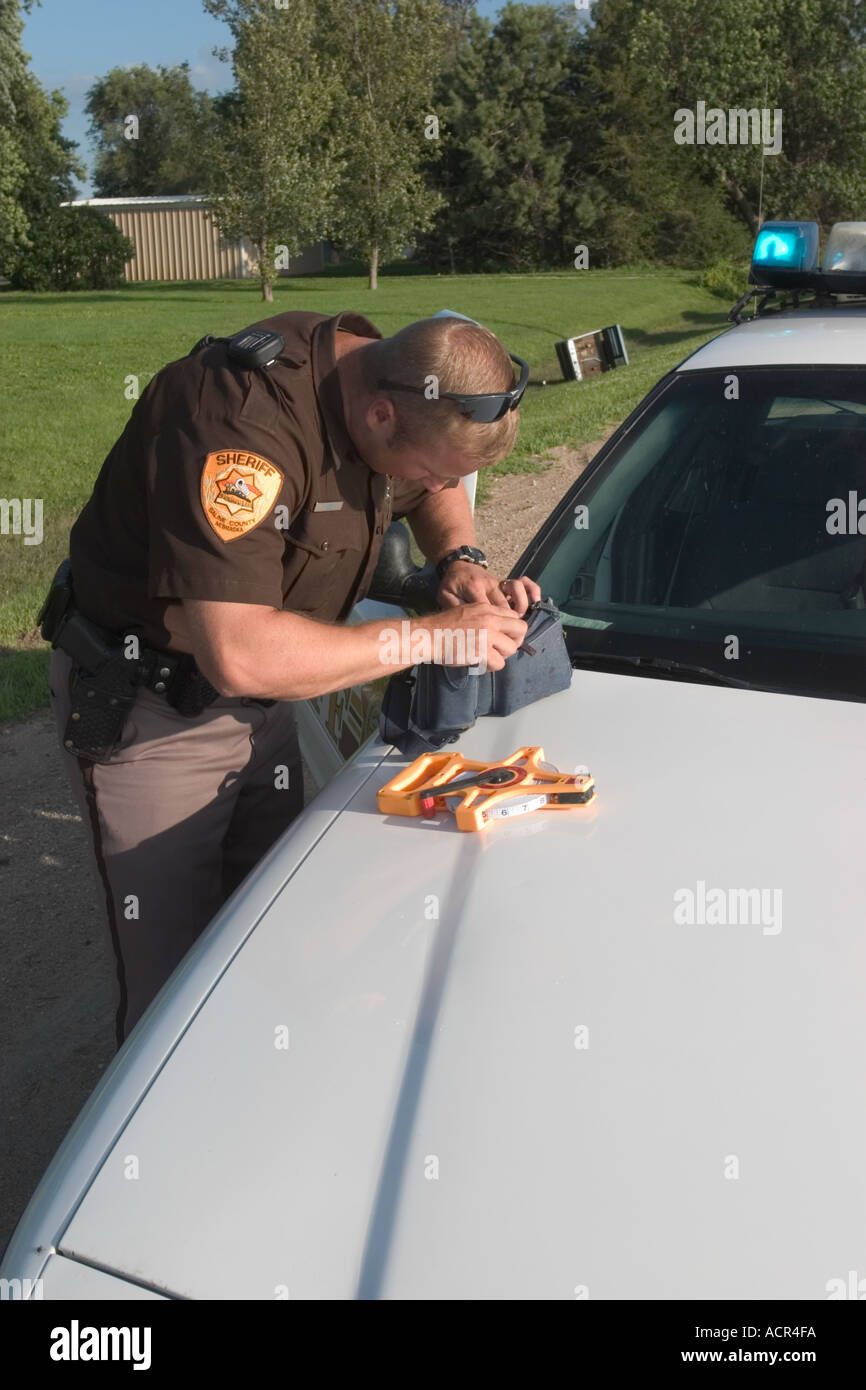 Verkehr Unfall Sheriff s stellvertretender durchsucht den Habseligkeiten des Individuums getötet in den Unfall, Kontaktinformationen zu finden. Stockfoto