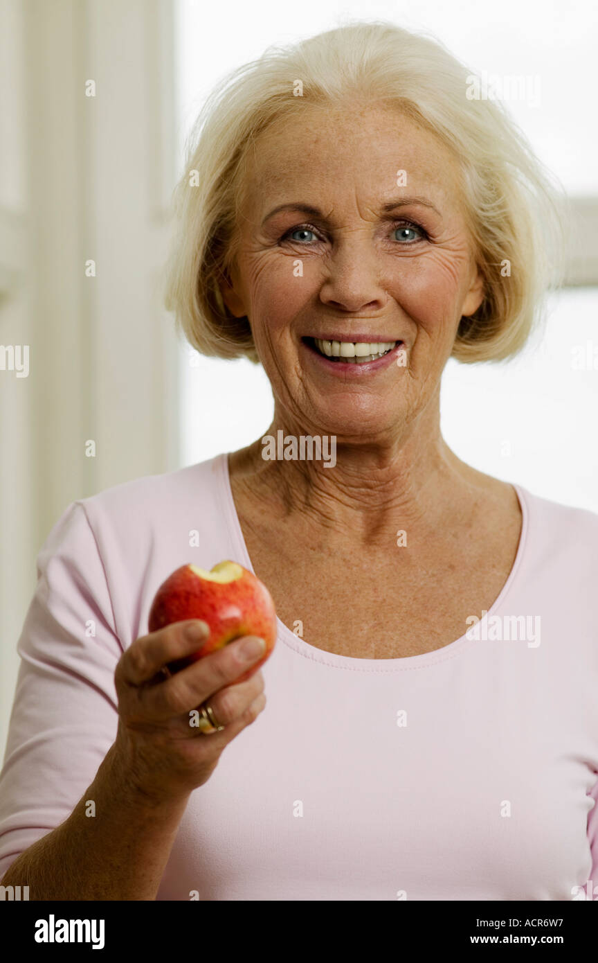 Ältere Frau Essen Apfel, lächelnd, Nahaufnahme, Porträt Stockfoto