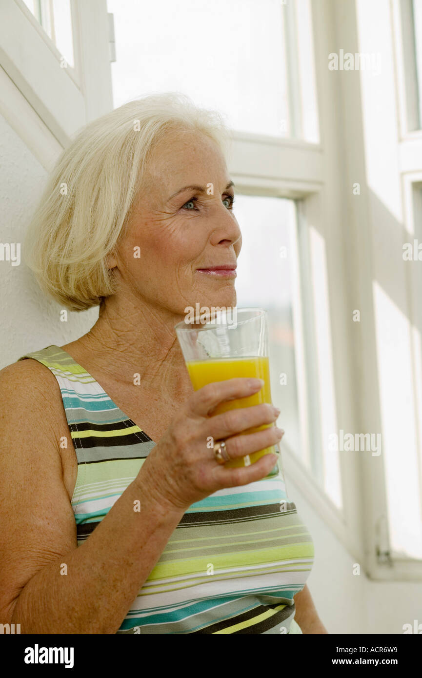 Ältere Frau mit Glas Saft, lächelnd, Nahaufnahme Stockfoto