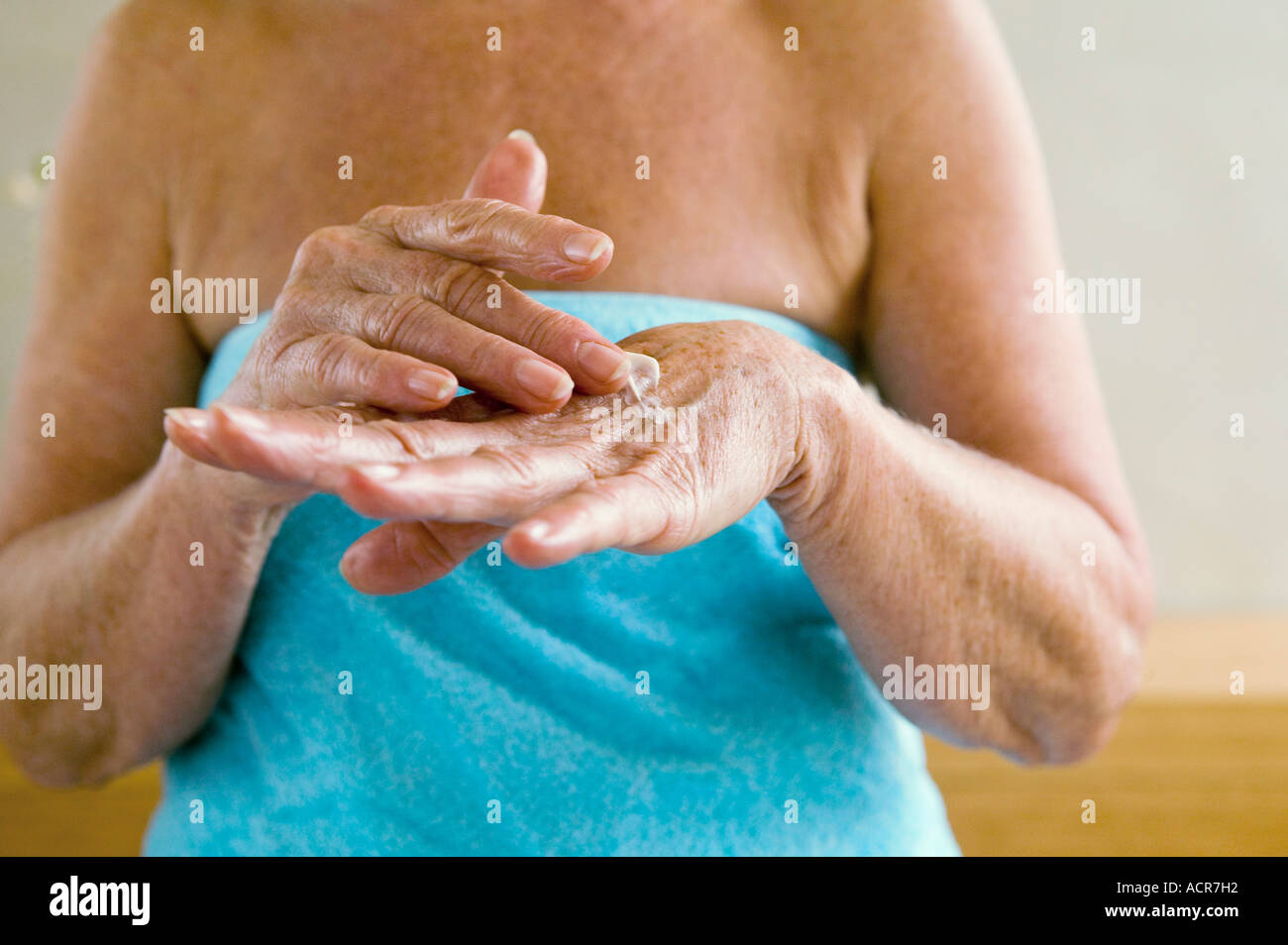 Ältere Frau gewickelt Handtuch, eincremen in Händen, Mittelteil, Nahaufnahme Stockfoto