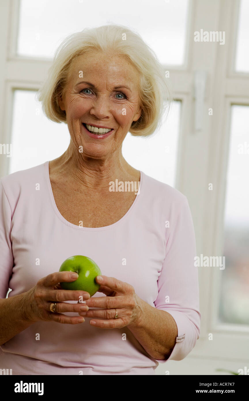 Ältere Frau mit Apfel, lächelnd, Nahaufnahme, Porträt Stockfoto