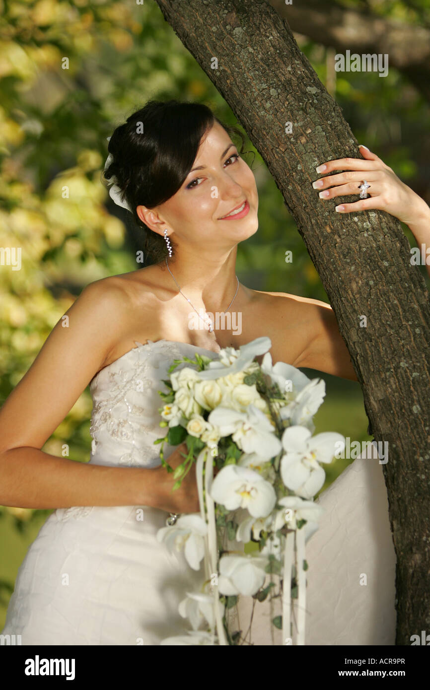 Porträt einer Braut stand neben einem Baum mit Blumenstrauß Stockfoto