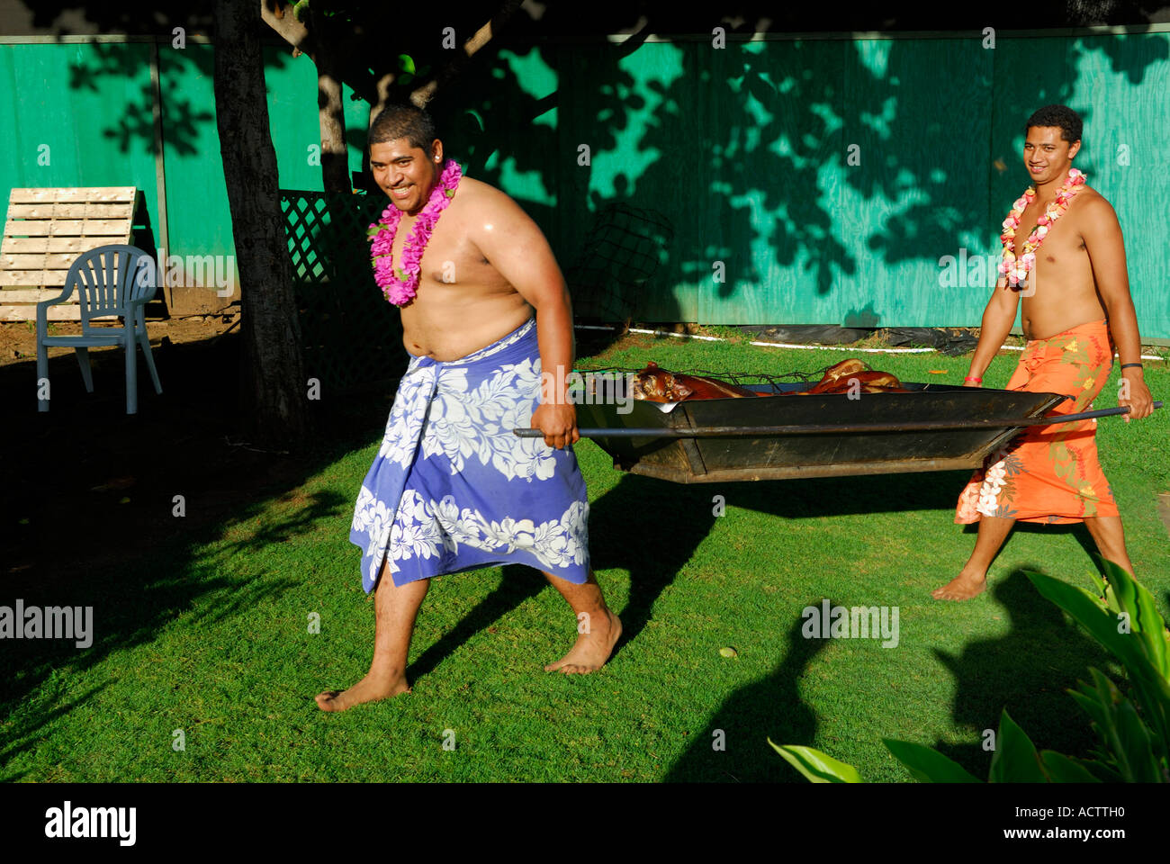 Zwei Männer tragen ein gebackenes Schwein nach der Imu an einem Luau auf Maui Hawaii Stockfoto Zwei Männer tragen ein gebackenes Schwein nach der Imu an einem Luau auf Maui Hawaii Stockfoto