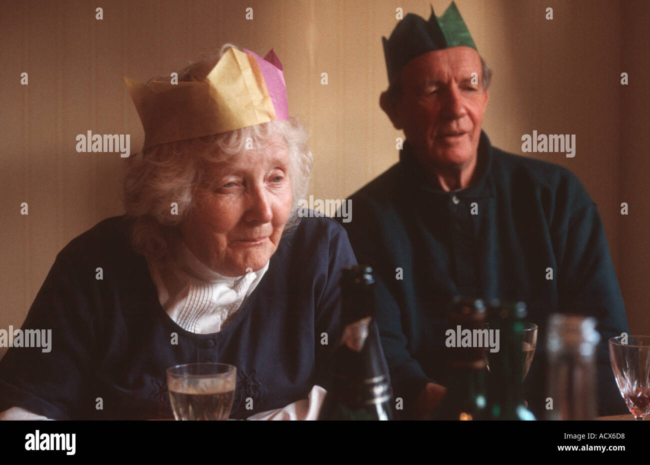 Eine ältere Rentner Senioren Frau und Mann in ihren Siebzigern tragen Partyhüte eher wehmütigen Blick Stockfoto