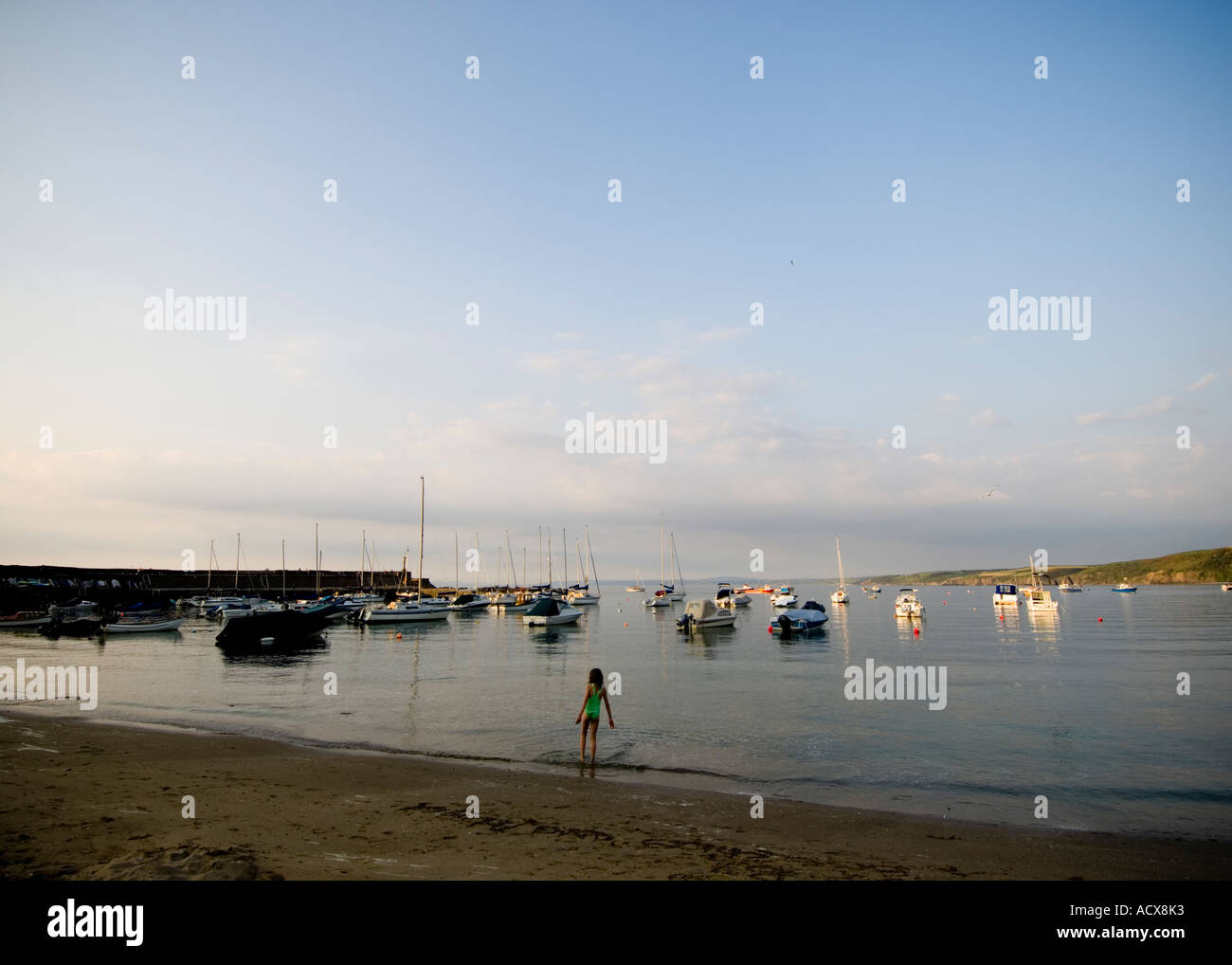 Mädchen im grünen Badeanzug zum neuen Kai Meer Ozeanwasser beruhigen ruhigen beschaulichen Cardigan Bay Sonnenuntergang Abenddämmerung Wales UK Stockfoto