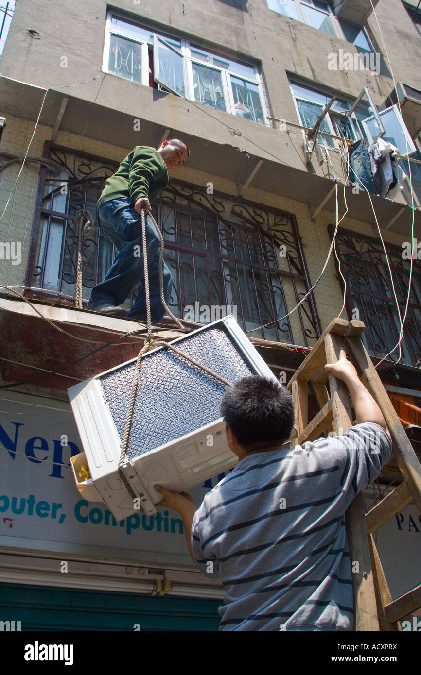 Arbeiter heben Klimaanlage im Fenster Installation Hongkong China Stockfoto