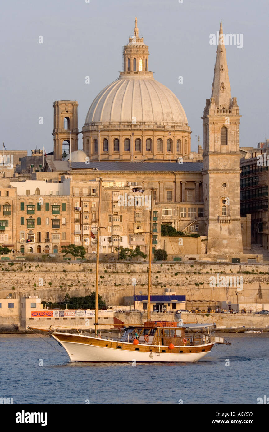 Yacht segelt bei Sonnenuntergang an Valletta vorbei. Nahaufnahme mit Kirchturm und Kirchturm. Stockfoto