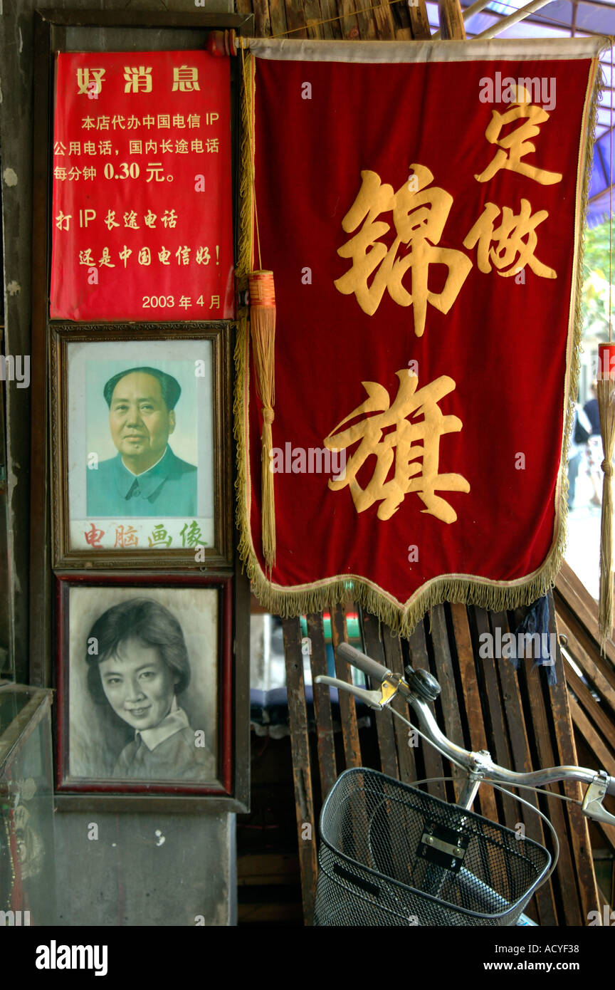 Sammlung von Bildern vor einem Haus in Wuxi China. Ein Porträt eines Mädchens, Bild des Vorsitzenden Mao, ein tiefes rotes Flaggen-Schild und Fahrrad. Stockfoto
