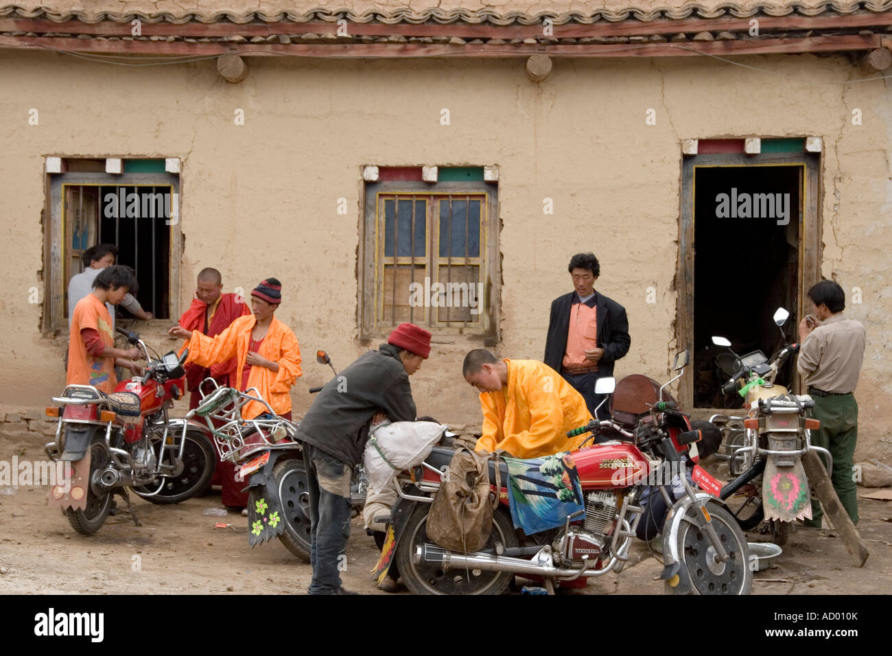 Mönche und einheimische Männer Befestigung Motorräder außerhalb des Mechanikers Outfit in Dzogchen Dorf, Provinz Sichuan, China. Stockfoto