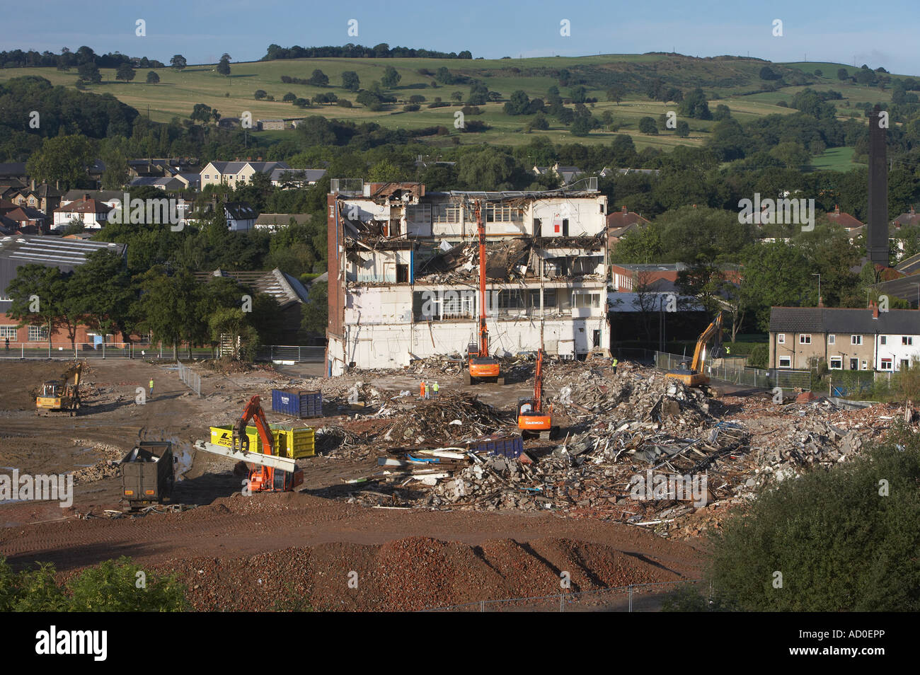 Hohe Ansicht der Abrissstelle (leere Fabrikhülle, schwere Raupenbagger arbeiten & Abrissgebäude, Schutthaufen) - Guiseley, England, Großbritannien. Stockfoto