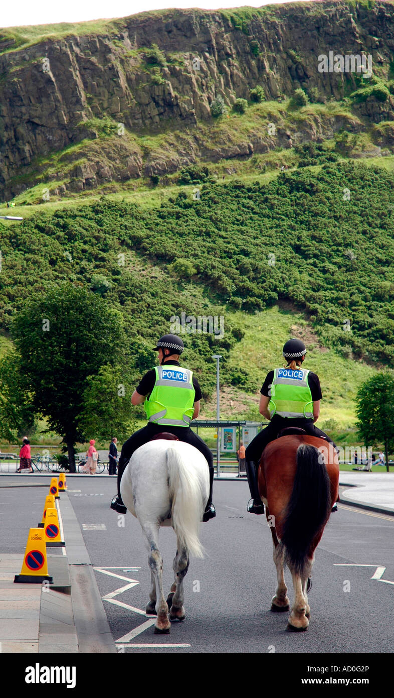 Zwei berittene Polizisten auf Pferden durch den Holyrood Park, Edinburgh mit Arthurs Seat in den Hintergrund, Schottland, Vereinigtes Königreich Stockfoto