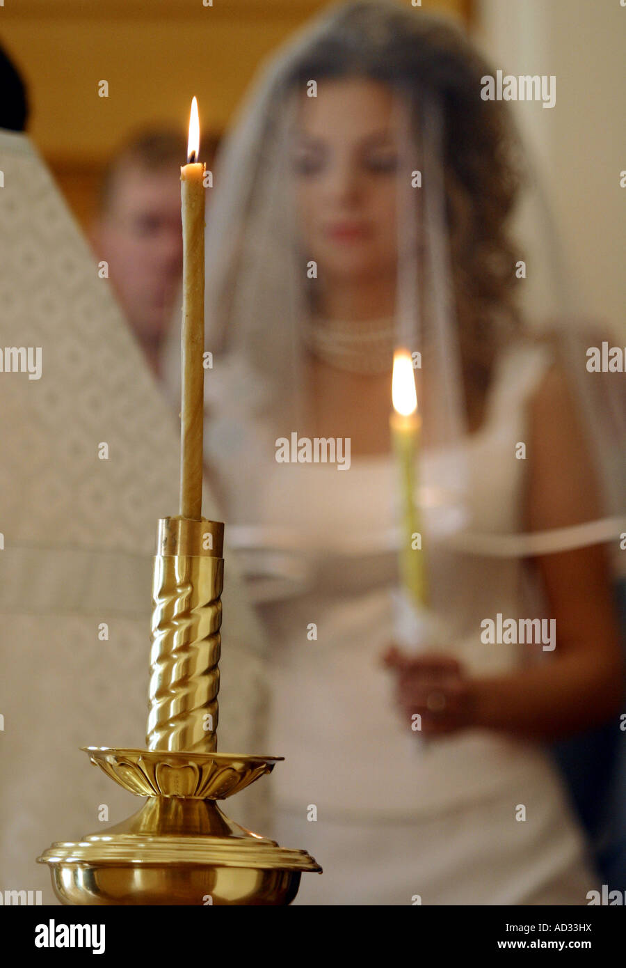 Braut hält eine Kerze am Altar der Kirche Stockfoto