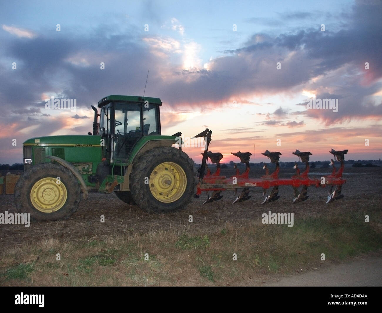 Sonnenuntergang Himmel & Silhouette des Bauern John Deere Traktor & Pflug geparkt in Ackerland in Essex England UK am Ende des im Feld ein Stockfoto