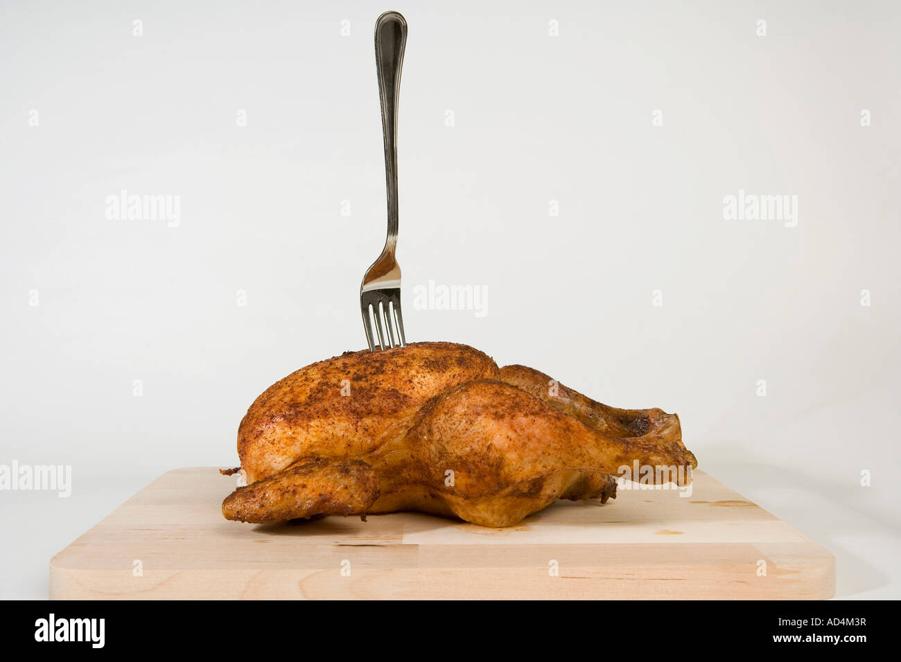 Eine Gabel in ein gebratenes Huhn stecken Stockfoto