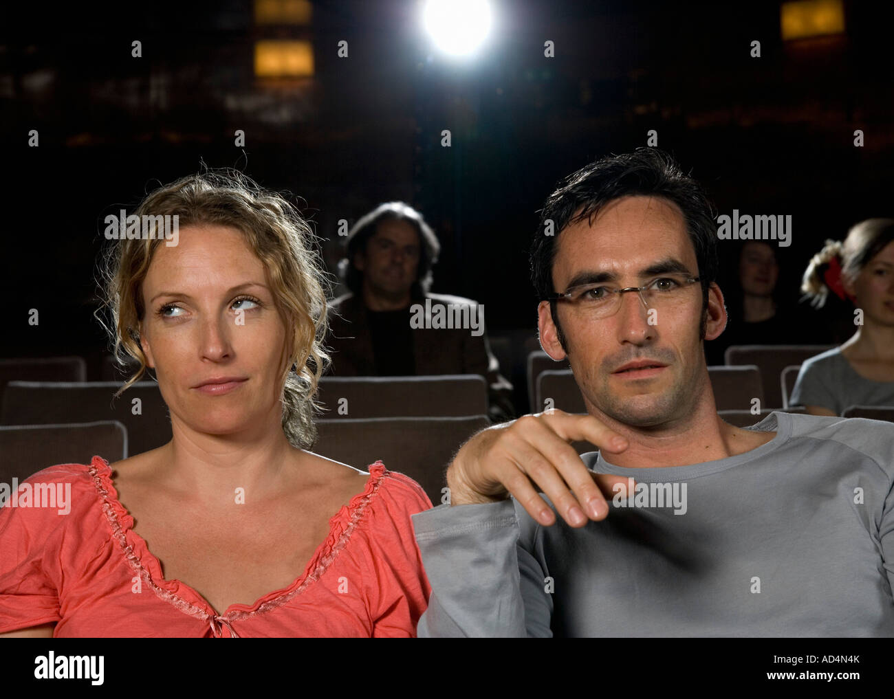 Eine Frau, die ihre Augen Rollen, neben einem Mann in einem Kino sitzen Stockfoto