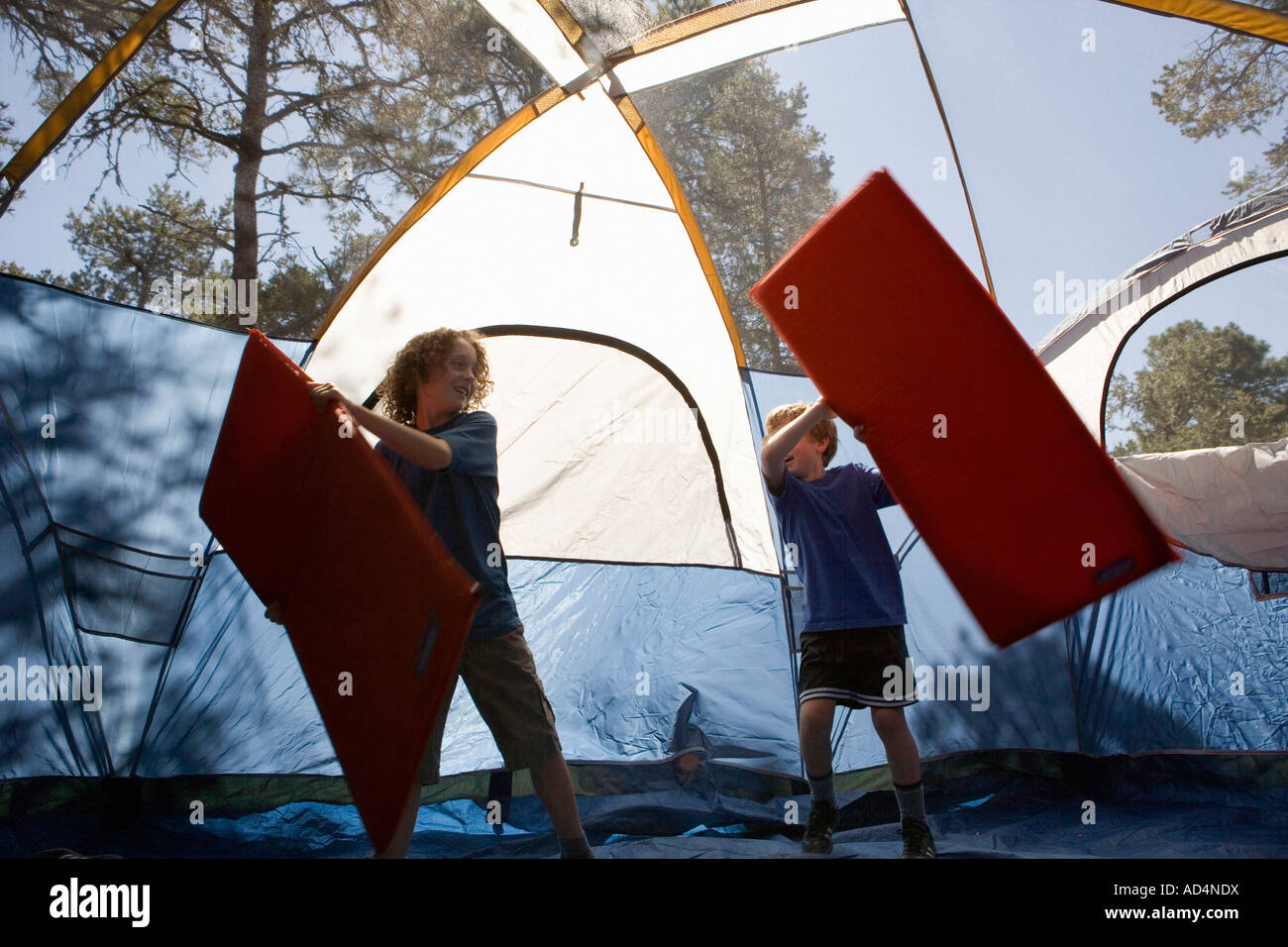Zwei Jungs spielen mit aufblasbaren Matratzen in einem Zelt Stockfoto
