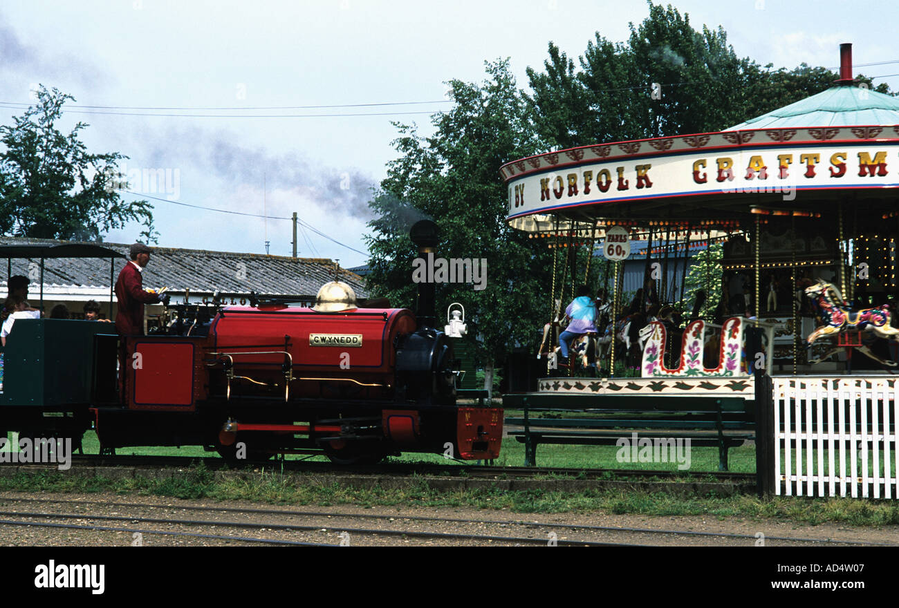 Schmale Lehre Eisenbahn nimmt Besucher mit auf eine Tour vorbei an eine Dampf angetriebene Karussell Norfolk Stockfoto