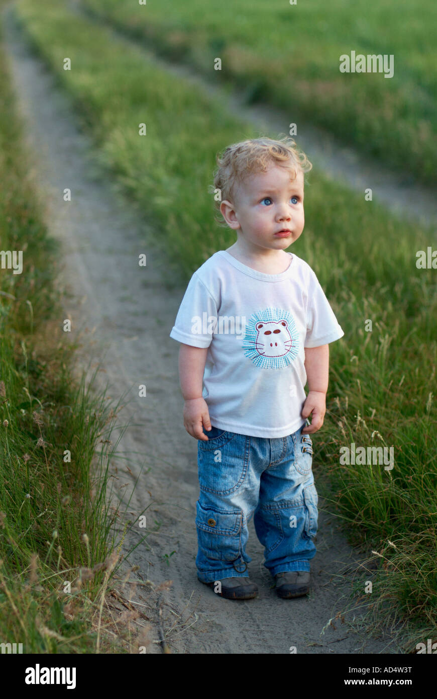 Ein kleiner Junge steht auf einem Feldweg Stockfoto