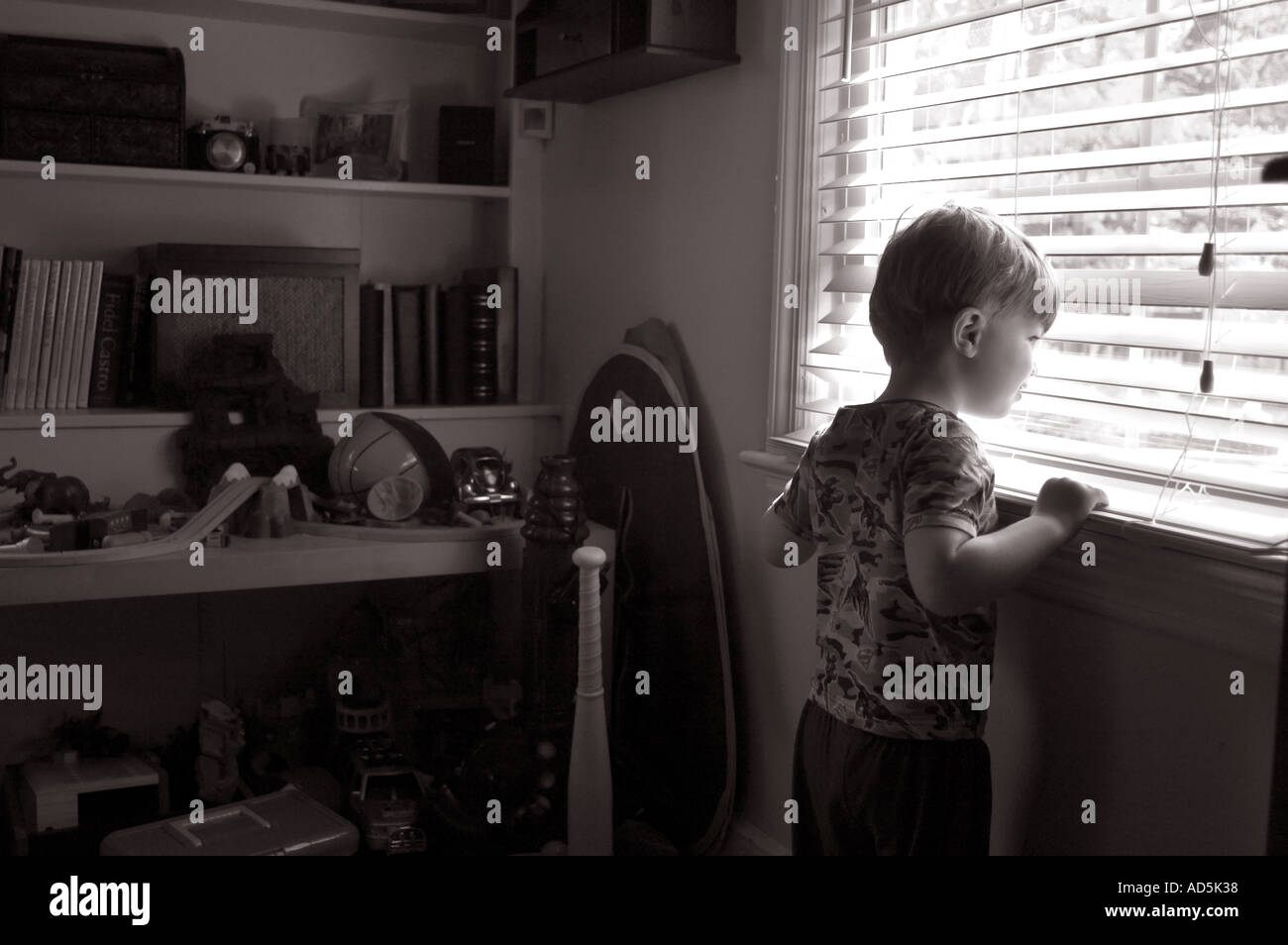 Kind aus Spielzimmer Fenster durch Jalousien beobachtete Außenwelt zu erforschen suchen Stockfoto