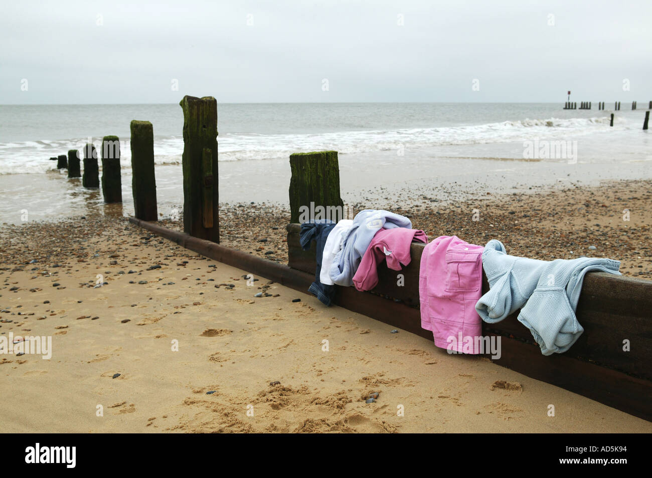 Konzept des Schwimmens im Meer in den Sommerferien am Strand mit Kleidung links auf eine Buhne Stockfoto