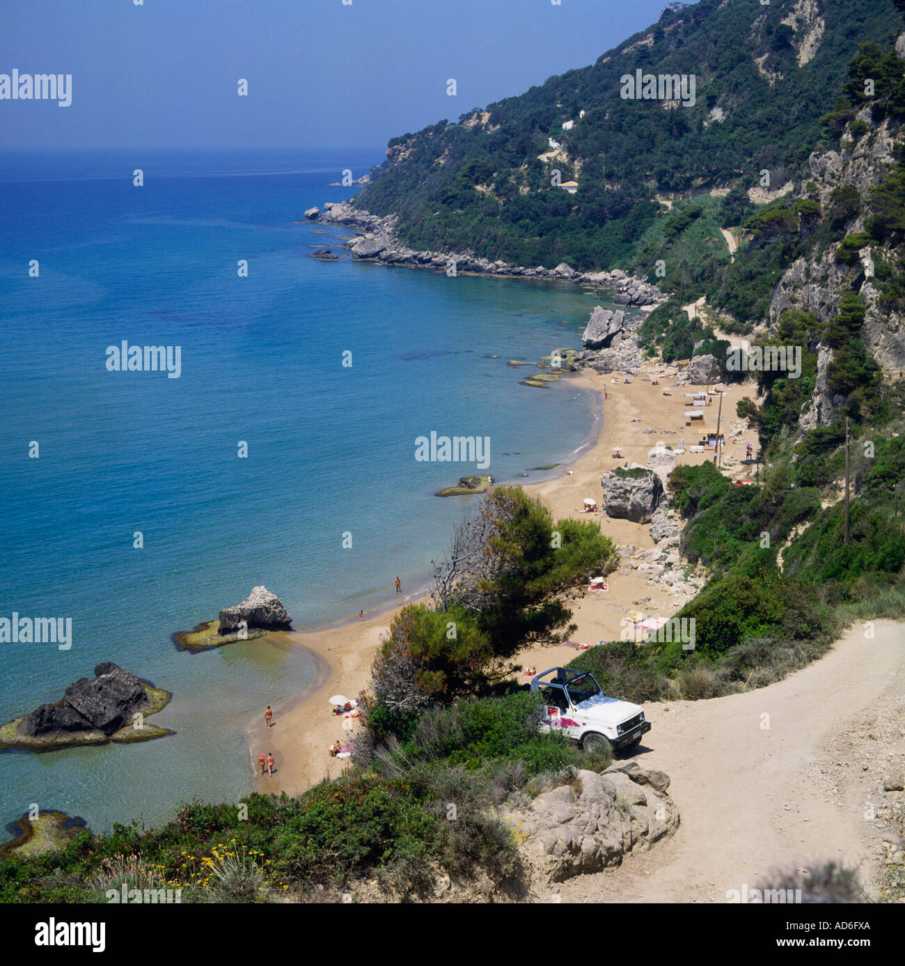 Blick auf schiere Baum bedeckt Klippen staubige Straße und Jeep zum Sandstrand mit Felsen Mirtiotissa Beach Korfu griechische Inseln Stockfoto