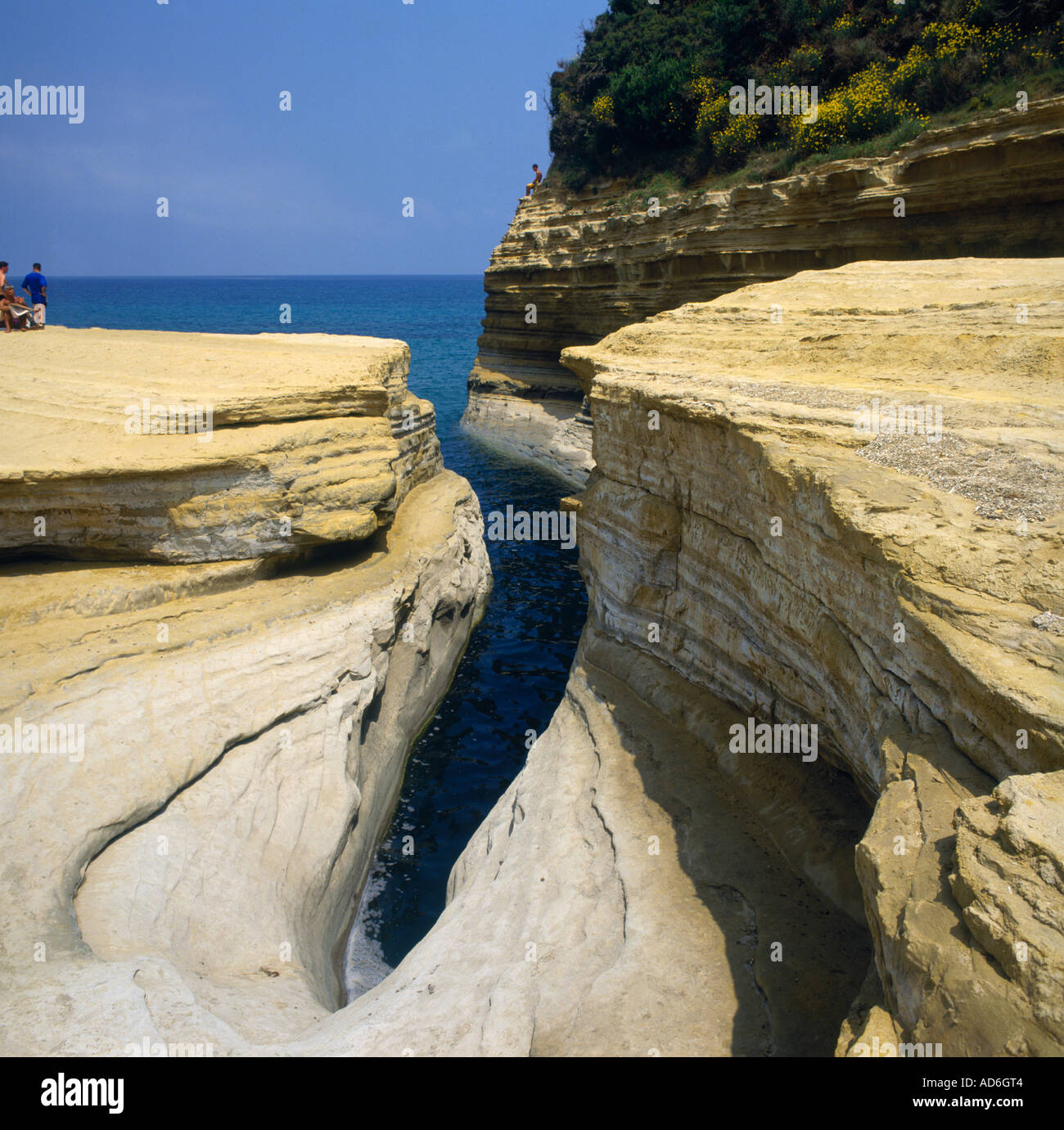 Wetter getragen Felsformation eine enge Schlucht mit Sonnenanbeter auf flachen Felsvorsprung in Sidari Korfu die griechischen Inseln Griechenlands Stockfoto