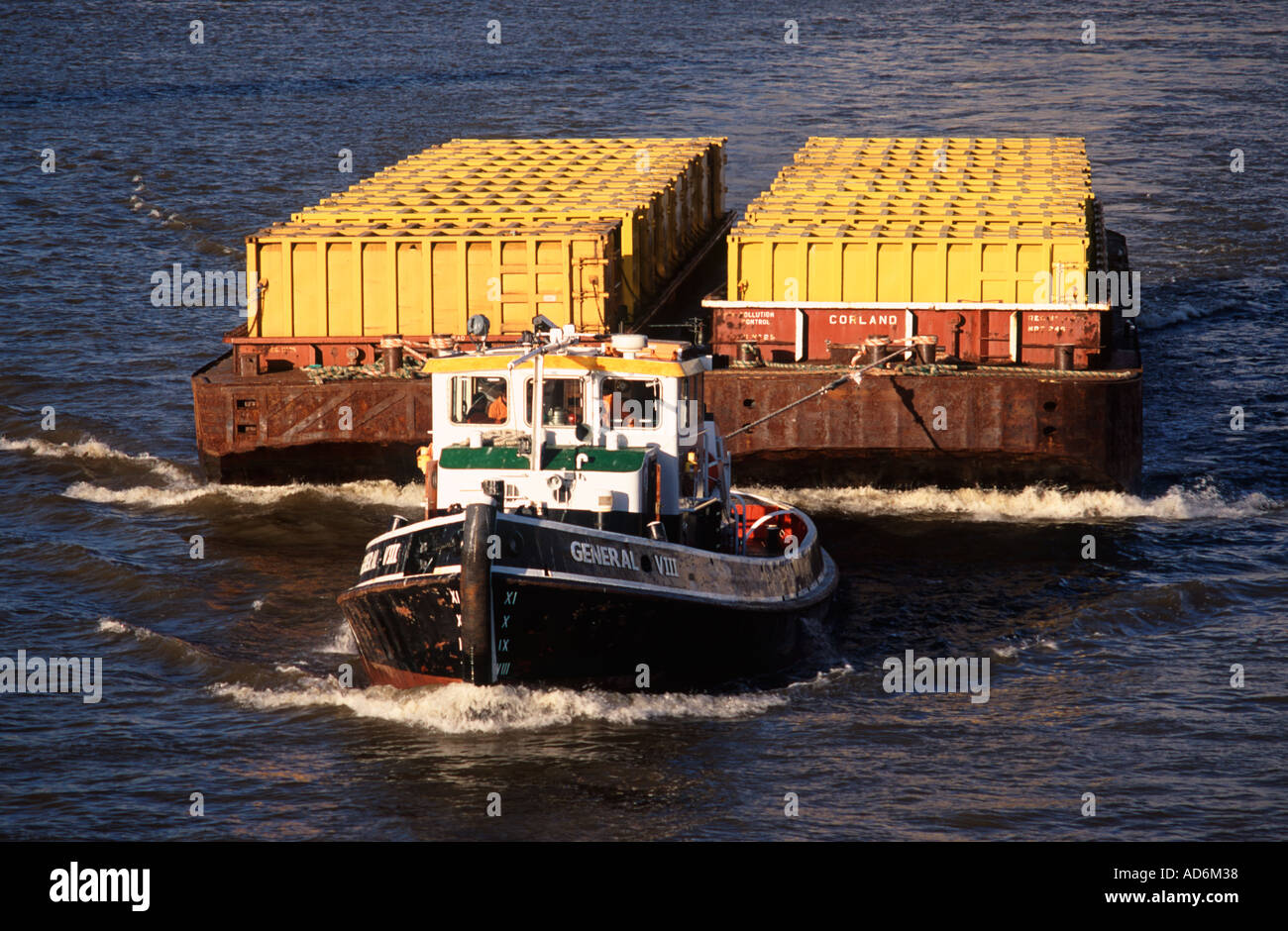 Schlepper ziehen ein paar Schiffe beladen mit gelben Containern – mit Hausmüll — auf der Themse, London Stockfoto