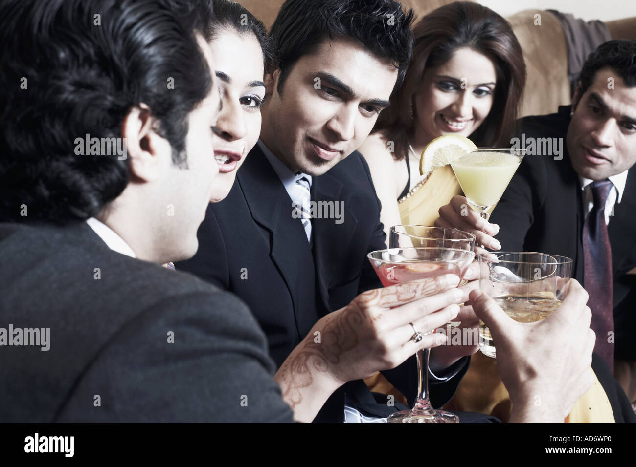 Nahaufnahme von drei junge Männer und zwei junge Frauen mit einen Toast mit Martini und Whisky Gläser Stockfoto