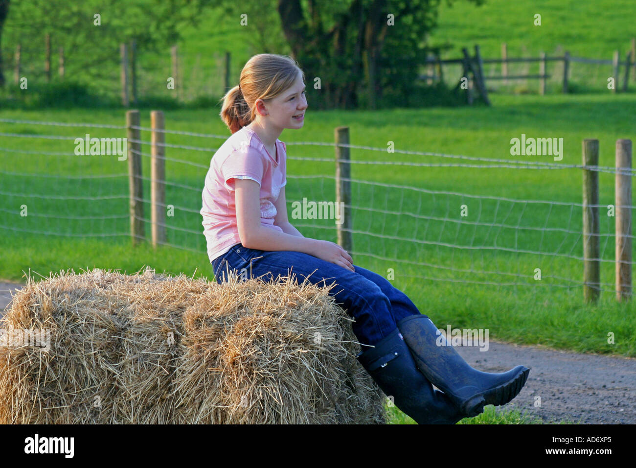 Blonde kurzhaarige Mädchen im Alter zwischen 10 und 16 Jahren sitzen auf einem Strohballen auf einem Feld in Nantwich. Stockfoto