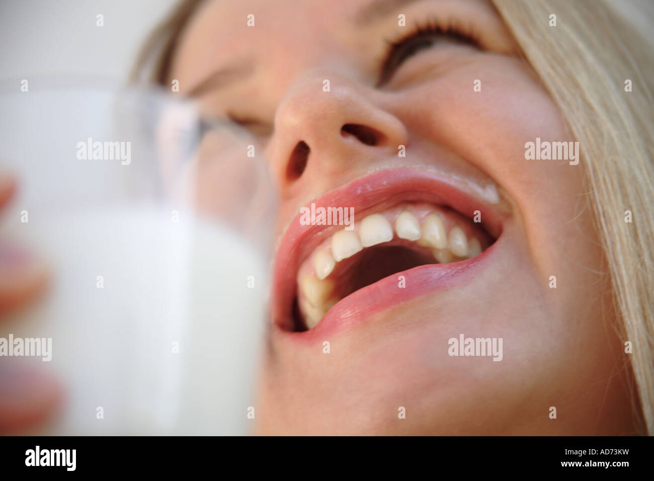 Junge, blonde Frau trinken Milch aus einem Glas, verwöhnt, in der Nähe von Stockfoto