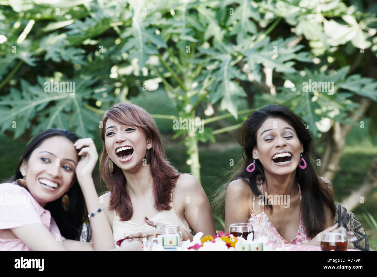 Zwei junge Frauen und ein junges Mädchen an einem Tisch sitzen und lachen Stockfoto