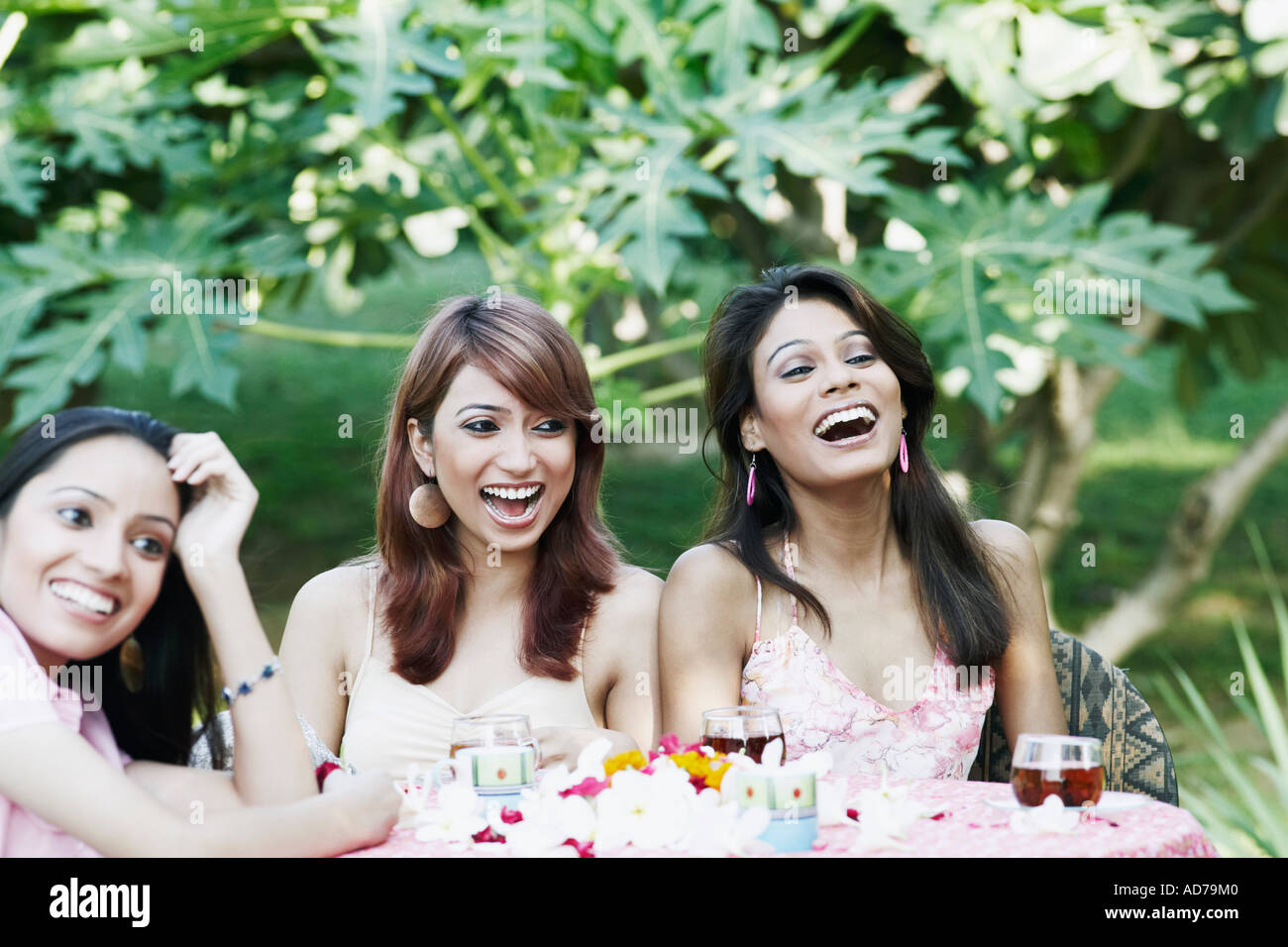 Zwei junge Frauen und ein junges Mädchen an einem Tisch sitzen und lachen Stockfoto
