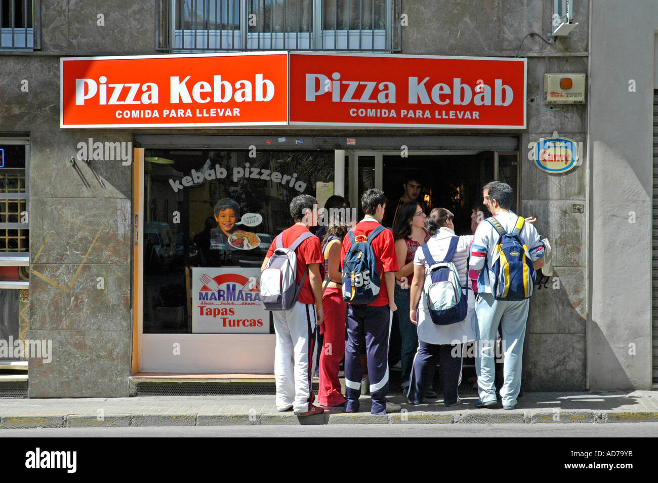Schulkinder mit Rucksäcken Jostleling in der Tür von einer Pizza und Kebab Shope, Elx, Elche, Costa Blanca, Spanien Stockfoto