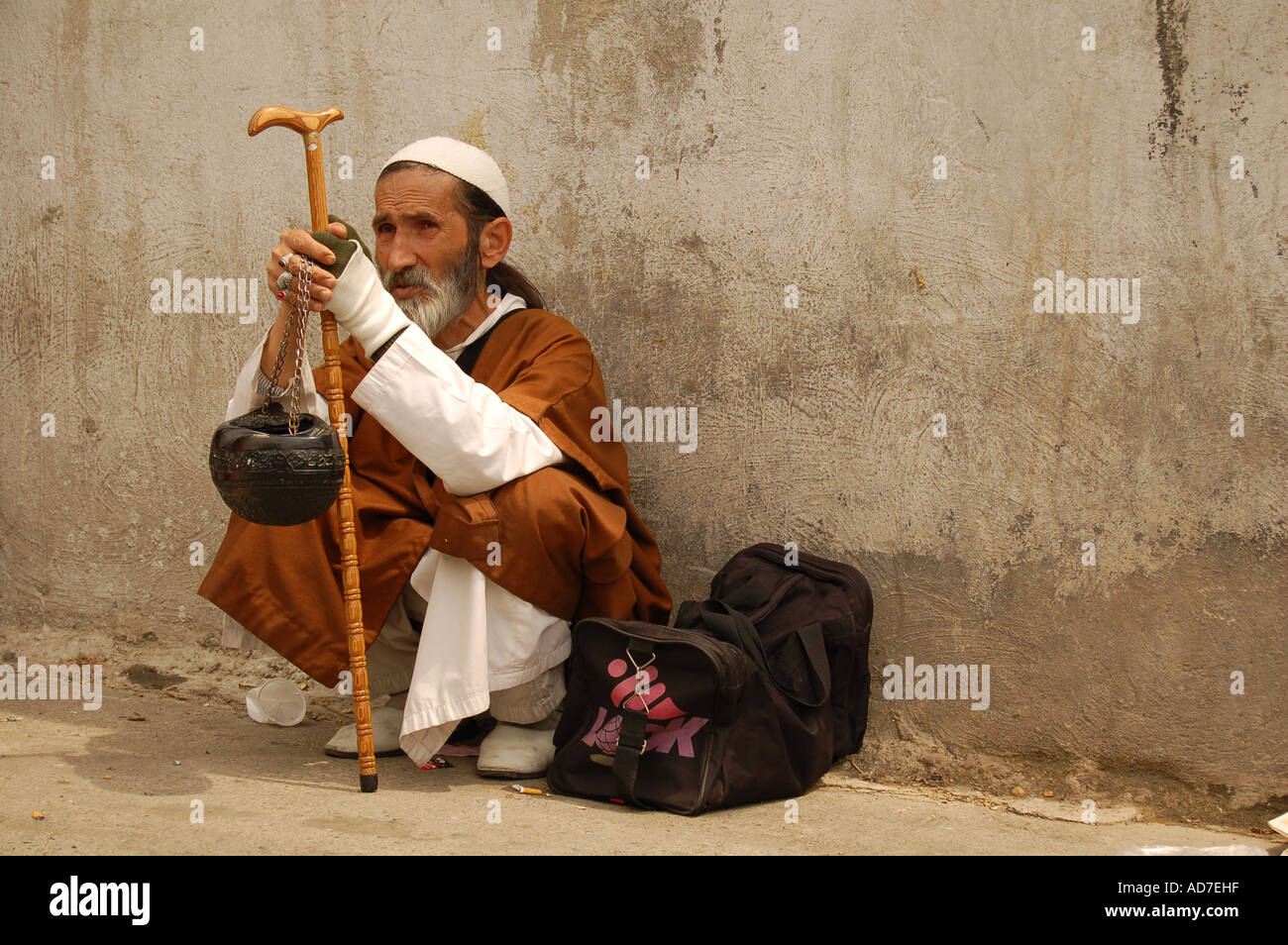 Derwisch in seiner traditionellen Kleidung saß auf dem Bürgersteig in Tadschrisch, Teheran, Iran Stockfoto