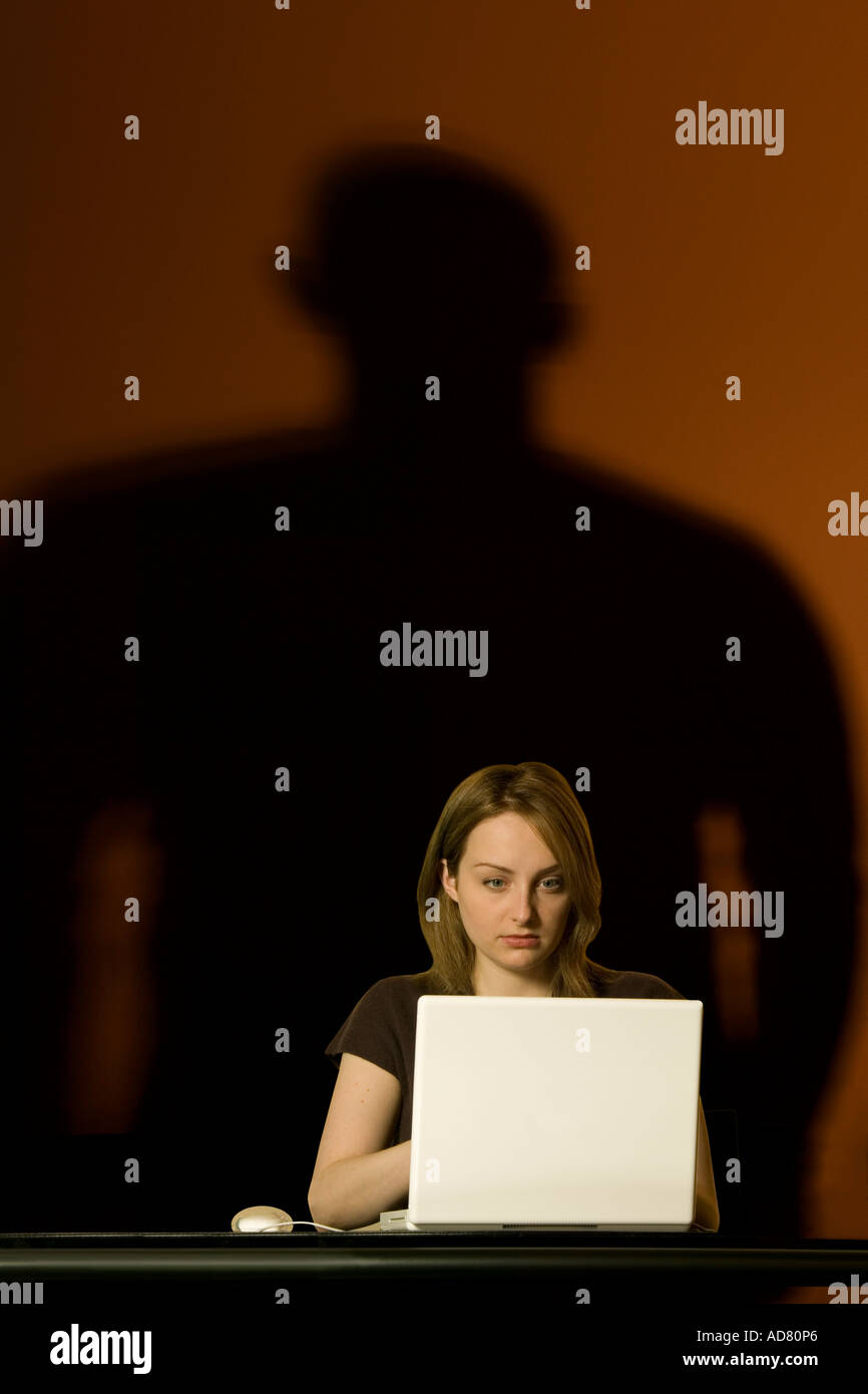 Frau auf Computer mit bedrohlichen Schatten Stockfoto