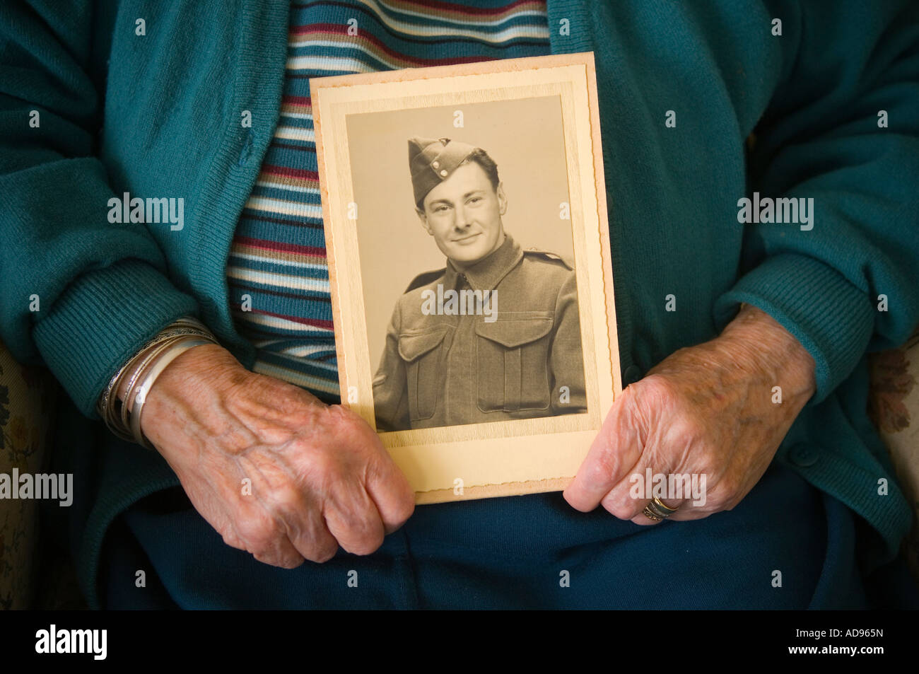 Ältere Dame hält ein Bild vom Mann als junger Soldat Stockfoto
