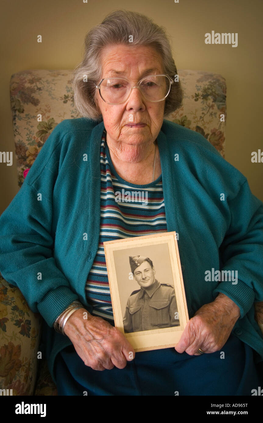 Traurig ältere Dame hält ein Bild ihres Mannes als junger Soldat Stockfoto