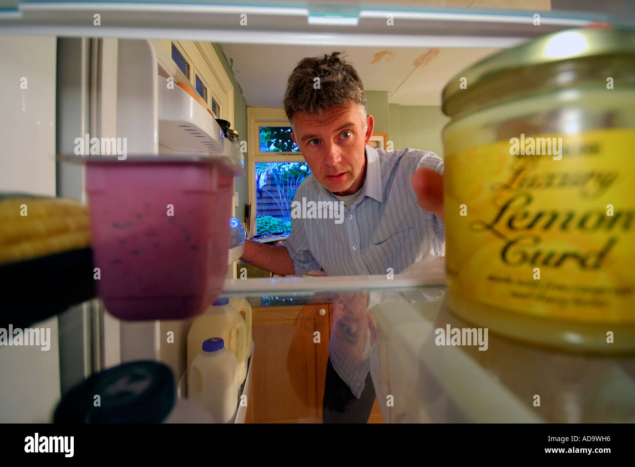 Mann auf der Suche und erreichen für Lebensmittel im Kühlschrank Stockfoto