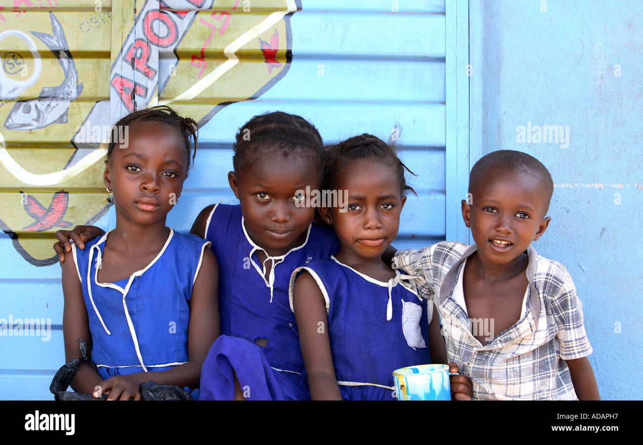 Horizontale helle Farbe Porträt oder vier Kinder in Sierra Leone, sitzen mit blauen Holzlatte Mauer gemalt mit Sardine Anzeige Stockfoto