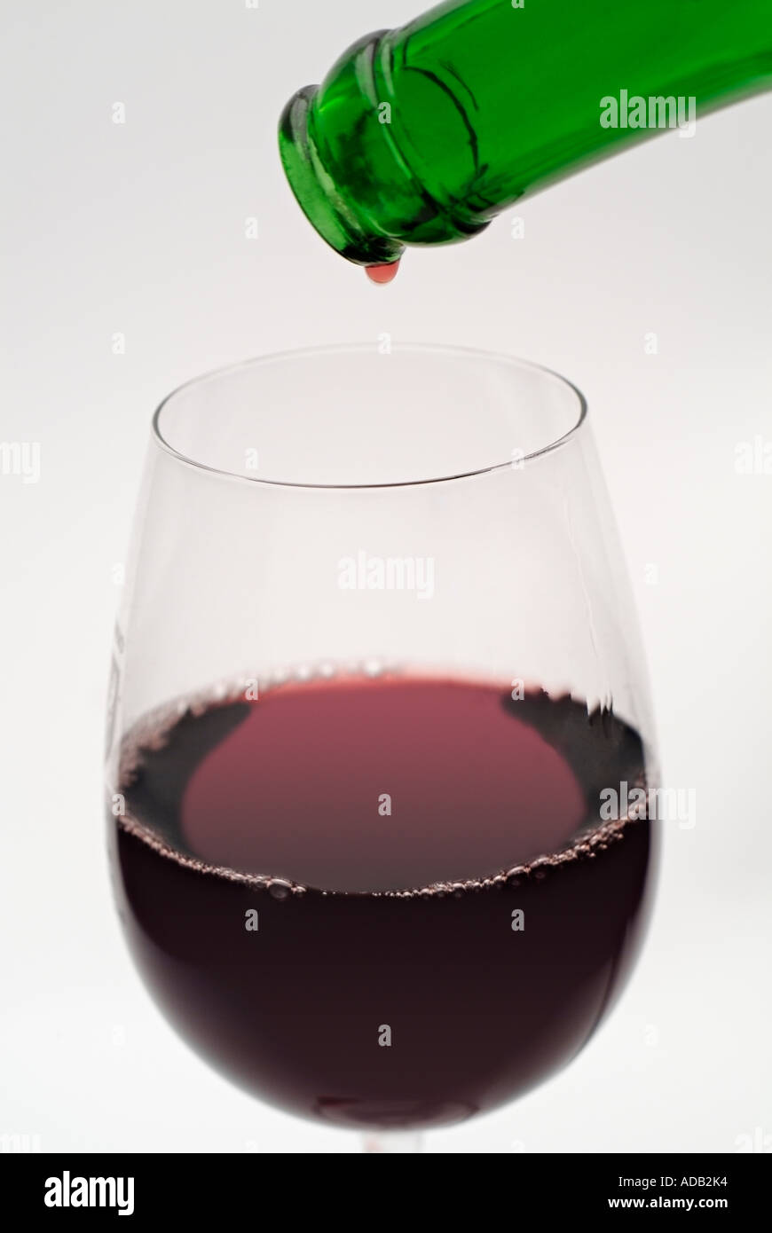 Nahaufnahme von den letzten Tropfen Rotwein aus der Flasche in ein Glas Wein in Strömen Stockfoto