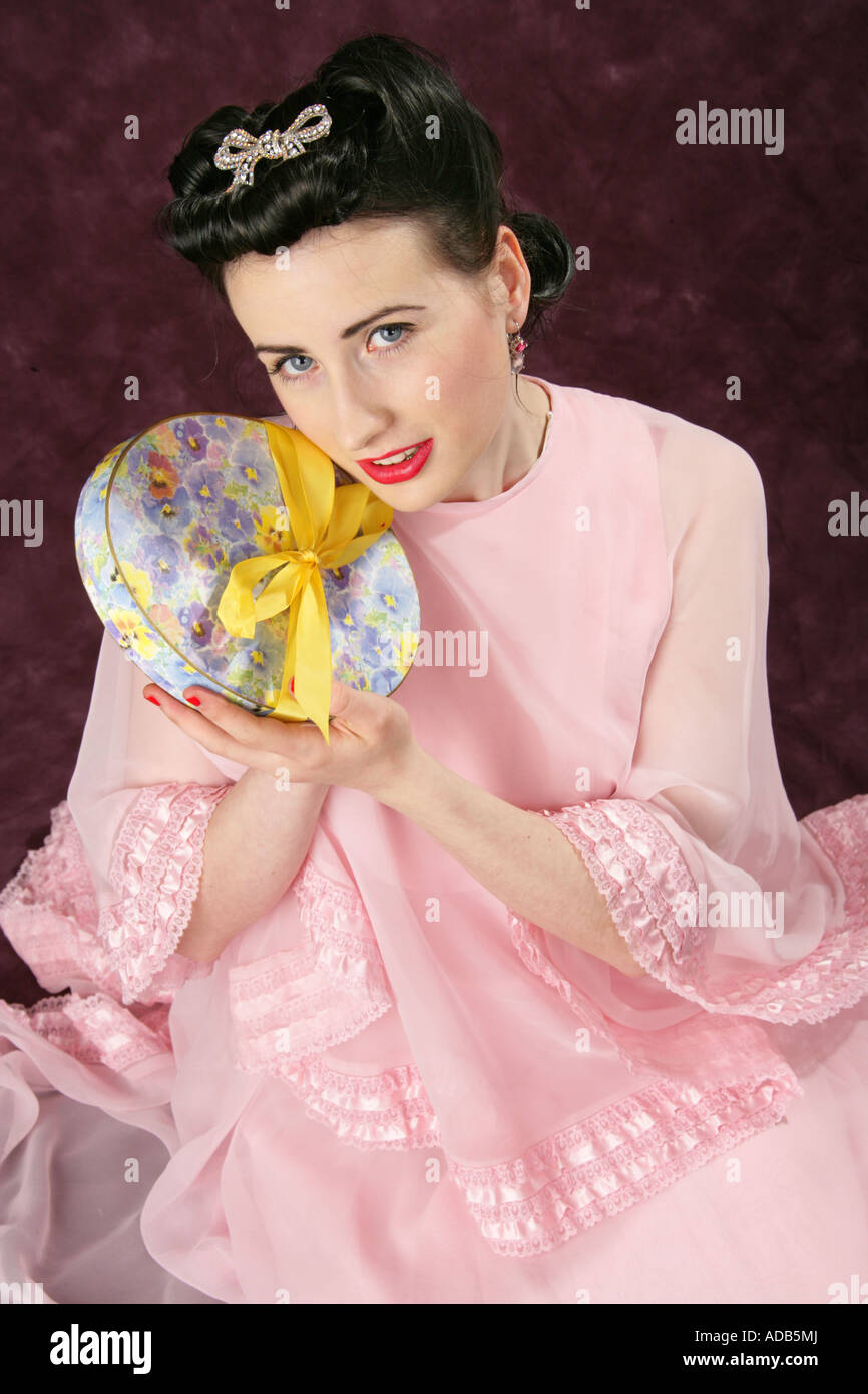 Pin Up Girl in einem rosa Kleid mit einem Feld von Candy mit einer gelben Schleife gebunden Stockfoto