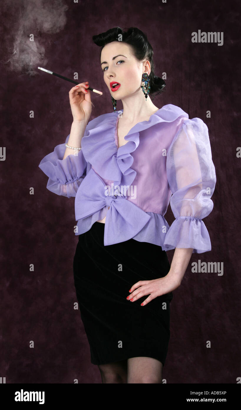 Ein Pin Up Girl in einem lila Bluse hält eine Zigarettenspitze und Rauchen Stockfoto