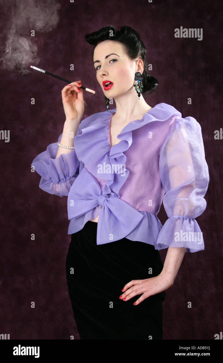 Ein Pin Up Girl in einem lila Bluse hält eine Zigarettenspitze und Rauchen Stockfoto