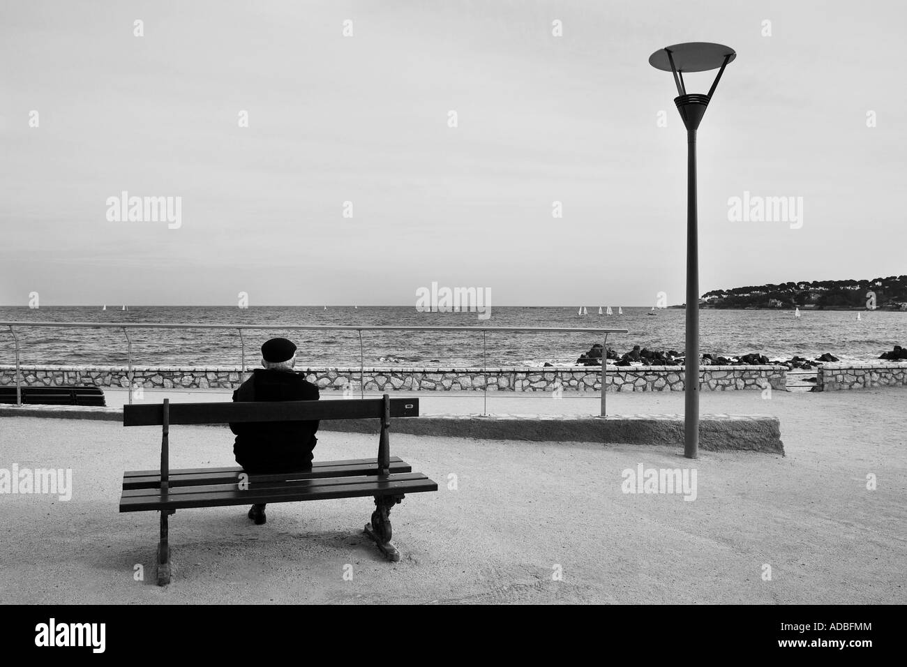 Mann auf der Bank neben dem Meer hohe Schlüssel schwarz und weiß Stockfoto