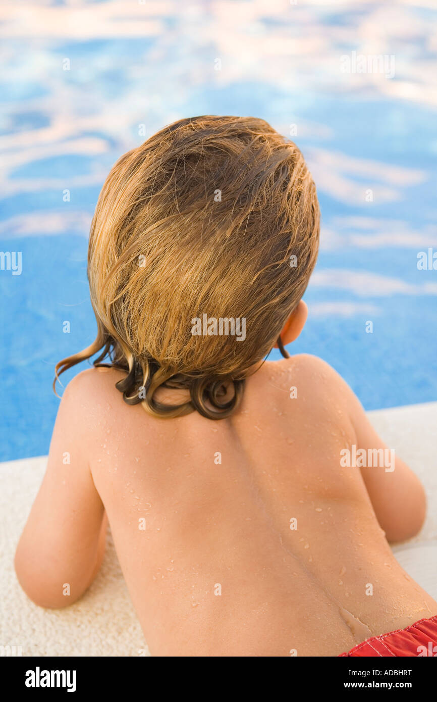 Kleiner Junge starrte auf das Wasser eines Schwimmbades, von hinten gesehen Stockfoto