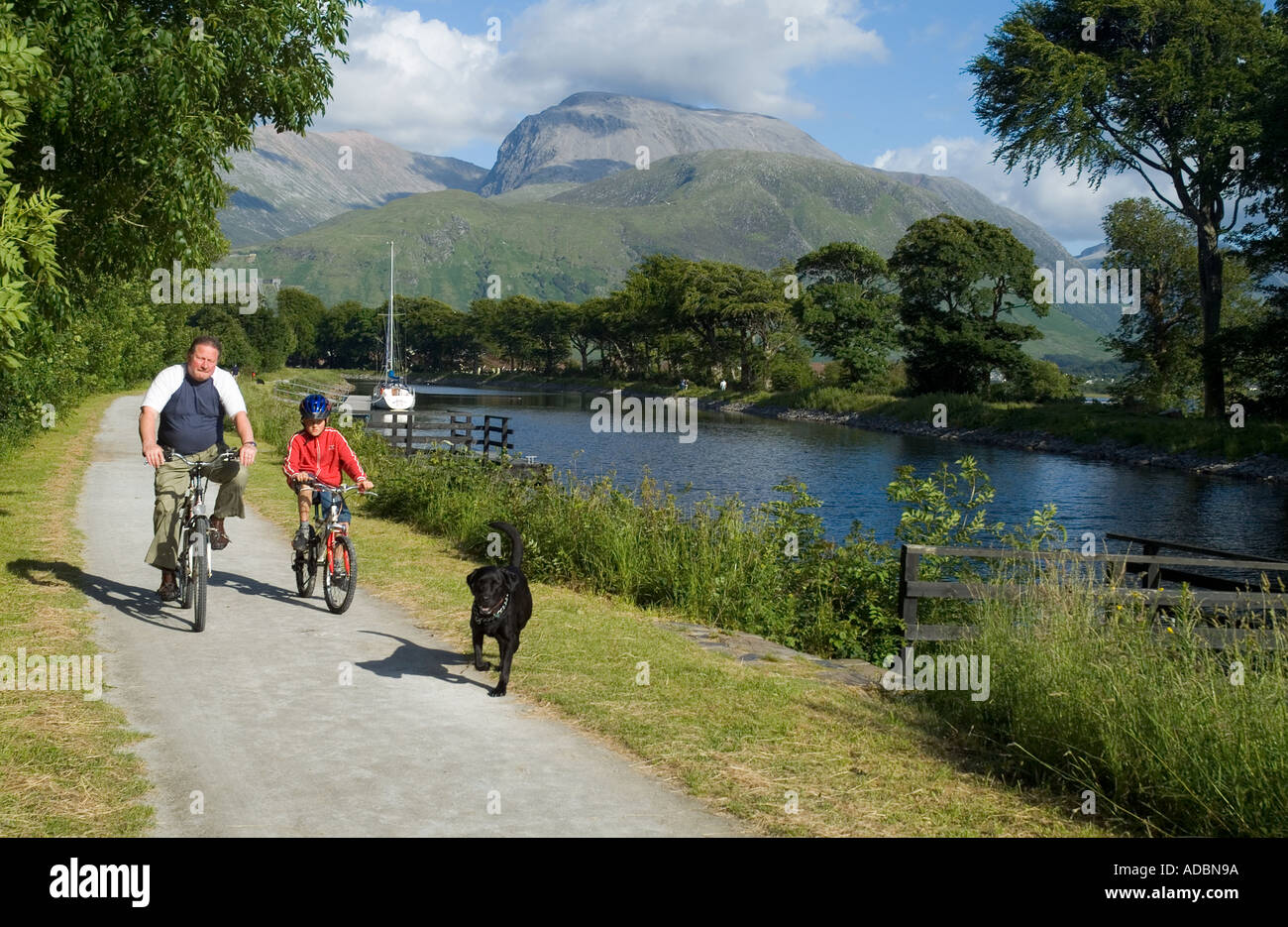 dh Corpach towpath schottland CALEDONIAN CANAL INVERNESSSHIRE zwei Mountainbike Radfahrer Radfahren auf dem Schleppweg Fahrräder Familie mit Hund fahren Untergeordnete Pfade durchlaufen Stockfoto