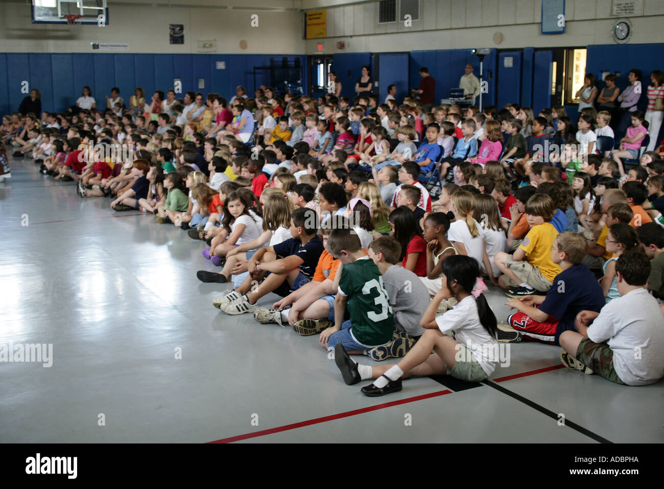 US-Studenten versammelten sich in einer Turnhalle sitzen auf Boden während einer Schulversammlung Stockfoto
